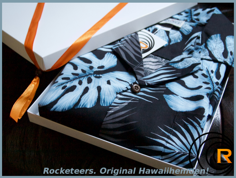 Das Bild zeigt original Hawaiihemd Blue Moon im Genschenkekarton. Blau Schwarz gefalten.